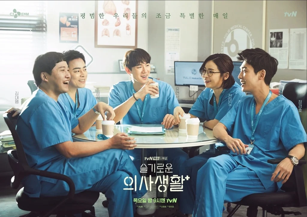 의사 옷을 입고있는 남자4 여자 1명이 테이블에서커피를 마시면서 얘기하고있다.