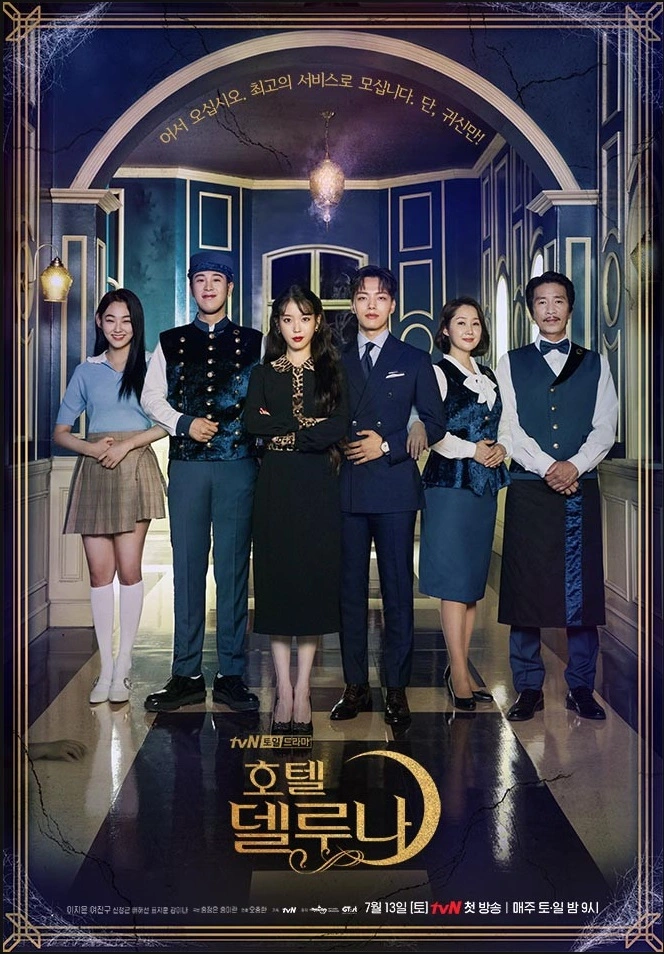 총 여섯명의 배우들이 호텔 로비에서 공손한 자세로 손님을 맞이하는 모습으로 앞을 보며 서있다. 아이유만 살짝 삐딱한 미소를 짓고있다.